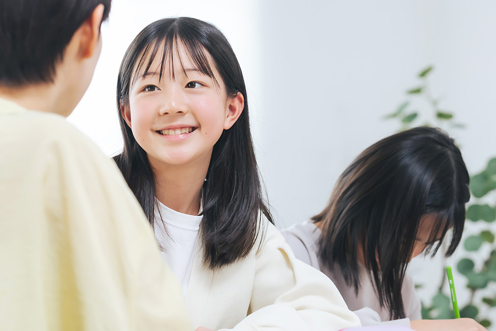 女子生徒が笑顔で会話しながら授業を受けている様子