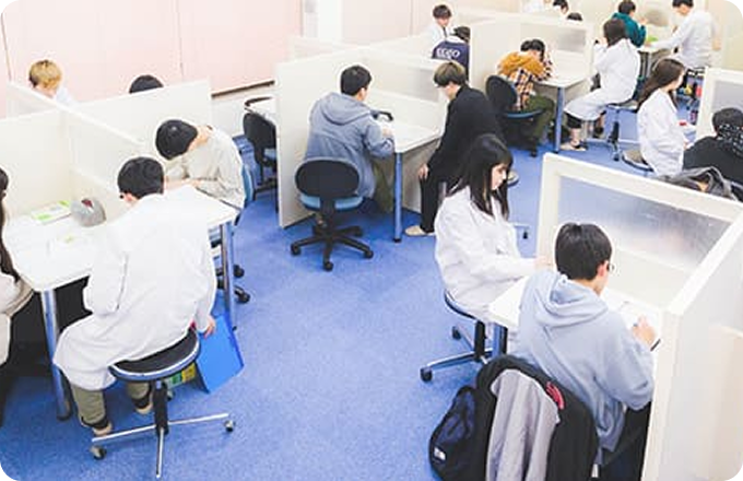 完全個別指導Goodの授業 一人ひとりの机が仕切られており、講師がついて教えている様子